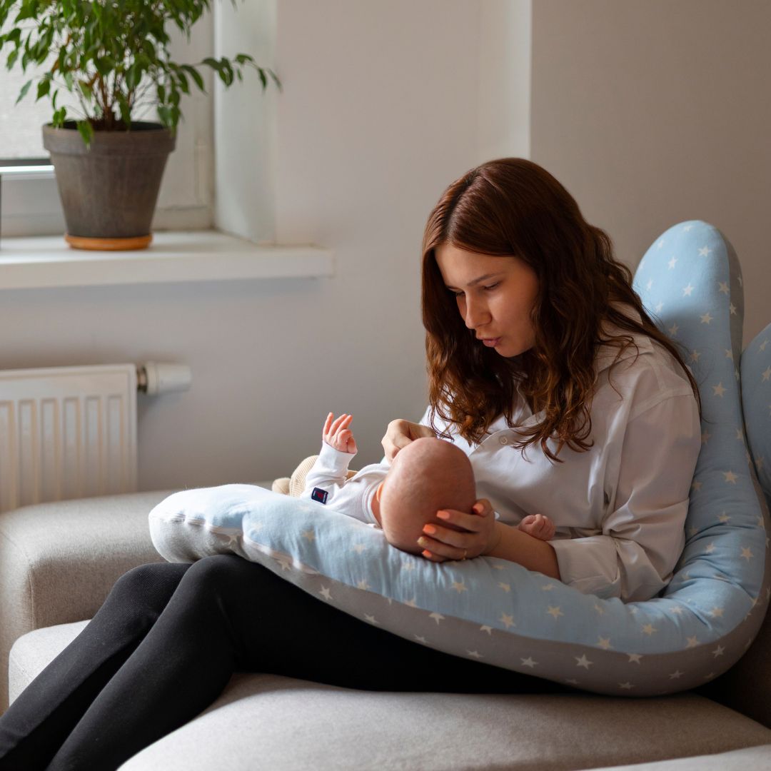 Maman allaitant son bébé confortablement installée avec un coussin d’allaitement en forme d’étoile