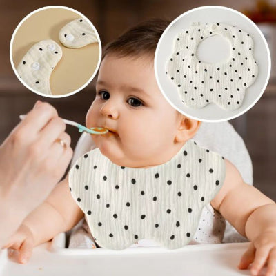 Bébé assis en chaise haute nourri à la cuillère, portant un bavoir bébé manche longue en coton motif pois noirs, bavoir coton repas absorbant et confortable.