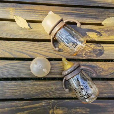 Deux biberons en PPSU avec tétine et capuchon oreilles d’ours, posés sur une table en bois, parfaits pour lait maternel ou eau.