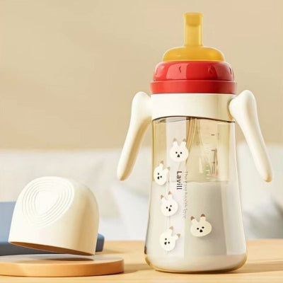 Biberon anti colique rouge de 300 ml avec bec en silicone et poignées adaptées aux petites mains.