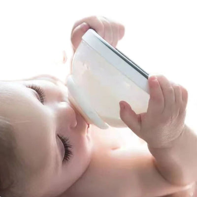 Bébé tenant un biberon en forme de sein et le buvant en toute autonomie.