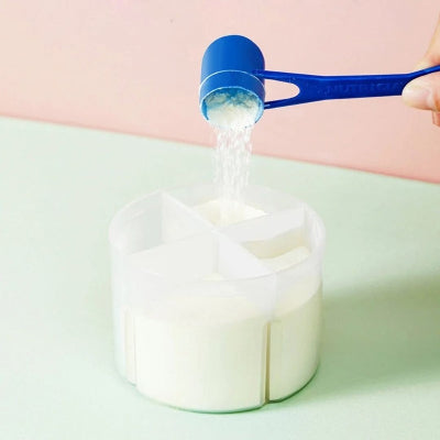 Remplissage d’un compartiment doseur avec du lait en poudre à l’aide d’une cuillère, pour des repas bébé prêts à l’avance.