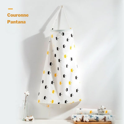 Cape d’allaitement blanche à motifs de couronnes jaunes et noires, conçue pour offrir intimité et liberté d’allaiter en extérieur.