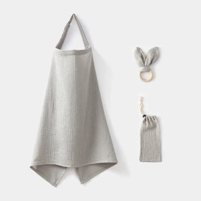 Cape d’allaitement en coton bio gris sauge avec anneau de dentition assorti et pochette de rangement, idéale pour allaiter bébé en toute discrétion.