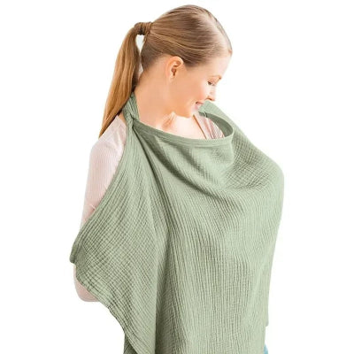 Maman allaitant discrètement avec une cape d’allaitement vert sauge, conçue pour offrir un cocon intime tout en gardant le contact visuel avec bébé.