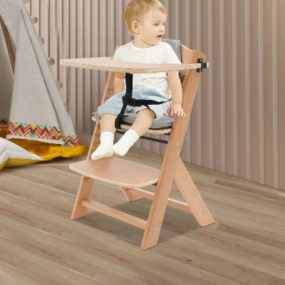 Bébé assis confortablement dans une chaise haute évolutive bois, design naturel avec plateau amovible et harnais sécurisé.