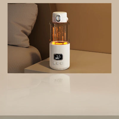 Chauffe biberon CozyHeat™ allumé en mode veilleuse à LED orange, posé sur une table de chevet, parfait pour les repas nocturnes de bébé.