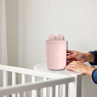 Chauffe biberon portable BabyWarm Pro™ posé sur une table à langer près du lit de bébé, toujours prêt pour une utilisation nocturne