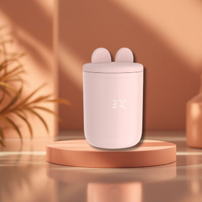 Chauffe biberon BabyWarm Pro™ rose affichant 37°C, mis en valeur sur un socle décoratif dans un intérieur chaleureux