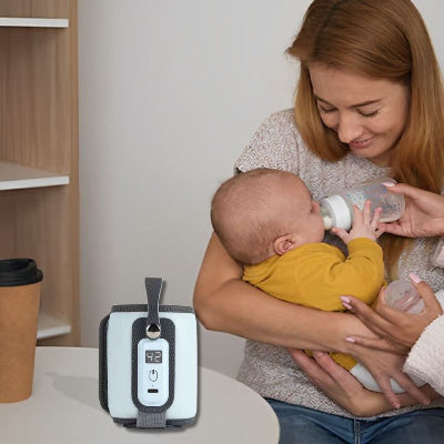 Chauffe biberon nomade posé sur une table pendant qu’une maman donne le biberon à son bébé dans un espace cosy.