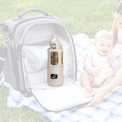 Chauffe biberon sans fil CozyHeat™ placé dans un sac à langer ouvert sur une couverture de pique-nique, idéal pour chauffer le lait lors des sorties en famille.