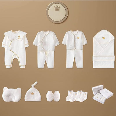 Illustration des différentes pièces du coffret naissance bébé Nanaël™ incluant pyjamas, oreiller, bonnet, moufles, chaussettes et boîte.