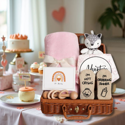 Coffret naissance bébé mis en valeur sur une table décorée pour un baby shower, entouré de cupcakes et de décorations roses en forme de cœur.