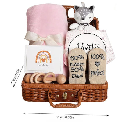 Coffret naissance bébé rose mesurant 22 x 17 cm, présenté avec une couverture douce, un hochet en bois, un doudou renard et des chaussettes imprimées dans un panier en osier.