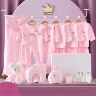 Coffret naissance bébé rose poudré composé de 20 pièces incluant vêtements, bonnet, oreiller, doudou et accessoires, présenté dans un décor raffiné.