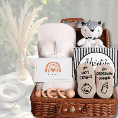 Coffret naissance bébé Toudou™ présenté dans une ambiance douce et naturelle avec éléments de décoration en rotin et blanc, mettant en valeur les produits pour nouveau-né.