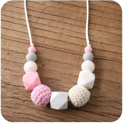 Collier d’allaitement blanc et rose avec perles crochetées texturées, parfait comme bijou de maternité ou idée de cadeau de naissance sensoriel et élégant.