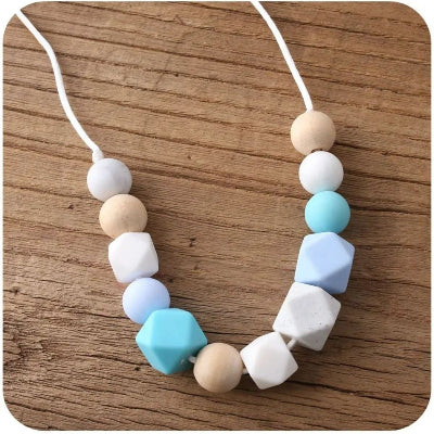 Collier d’allaitement silicone bleu pastel et perles en bois naturel, parfait pour apaiser les gencives et garder bébé concentré lors du portage ou des câlins.