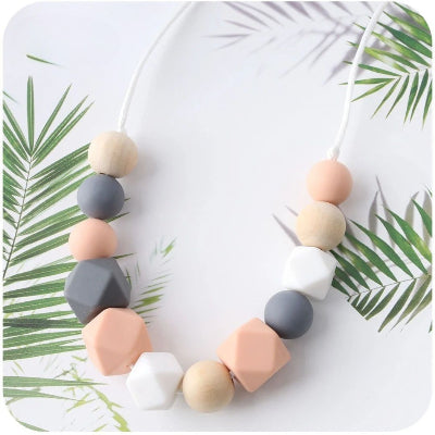 Collier d’allaitement au design moderne avec perles pêche, gris et blanches, pour soulager les douleurs dentaires de bébé tout en complétant votre tenue quotidienne.
