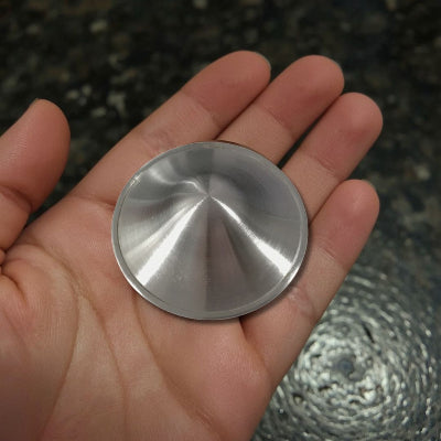 Coupelle d’allaitement en argent pur tenue en main, montrant la finition concave adaptée à la protection du mamelon
