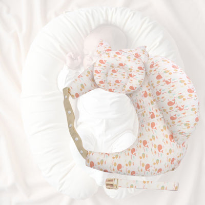 Bébé installé confortablement sur un coussin d’allaitement motif baleines avec oreiller intégré et inclinaison pour digestion, idéal après les repas.