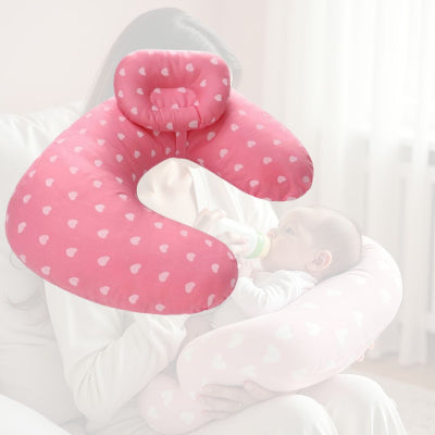 Bébé nourri au biberon confortablement installé sur un coussin d’allaitement rose à cœurs, parfait pour l’allaitement mixte ou au biberon.