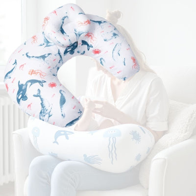 Maman nourrissant son bébé avec un coussin d’allaitement imprimé animaux marins, conçu pour réduire les tensions au niveau des bras et faciliter la succion de bébé.