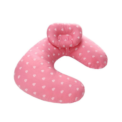 Coussin d’allaitement rose à motifs cœurs blancs, forme ergonomique pour assurer le confort d’allaitement à la maison ou en déplacement.