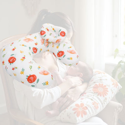 Maman allaitant son bébé avec un coussin d’allaitement à fleurs rouges et orange, garantissant une position ergonomique et un confort optimal.