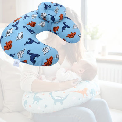 Maman utilisant un coussin d’allaitement GraphiDino™ bleu ciel avec bébé, installée confortablement sur un canapé en pleine séance d’allaitement serein.