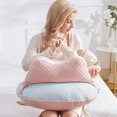 Maman nourrissant son bébé avec le coussin d'allaitement CozyNest en coloris bleu et rose