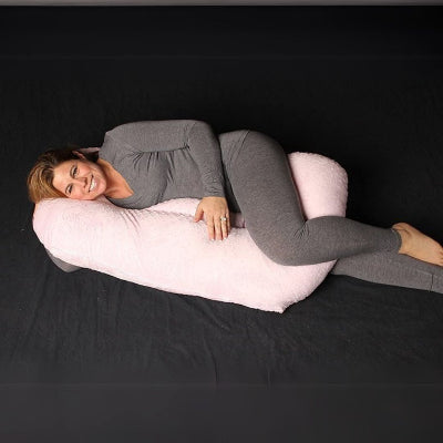 Femme enceinte allongée sur un coussin d’allaitement jumeaux rose, utilisé ici comme coussin de grossesse pour dormir.