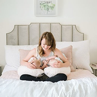 Maman allaitant ses jumeaux confortablement installée au lit avec un coussin d’allaitement jumeaux blanc.
