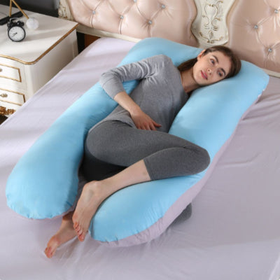 Femme allongée et détendue sur un coussin de grossesse bleu ciel, utilisé pour se relaxer et améliorer le confort postural.