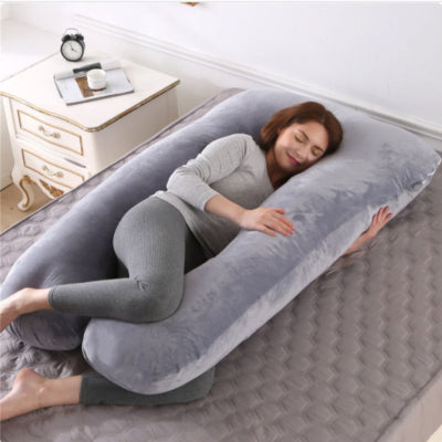Jeune maman dormant sur un coussin de grossesse gris clair, offrant un excellent soutien dorsal et un confort de maternité optimal.
