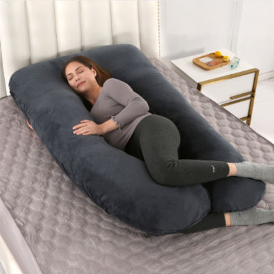 Femme enceinte allongée confortablement sur un coussin de grossesse noir en forme de U, idéal pour un sommeil latéral réparateur.