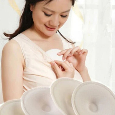 Jeune maman insérant un coussinet d’allaitement doux et absorbant dans son soutien-gorge pour éviter les fuites de lait, accessoire indispensable pour un allaitement serein.