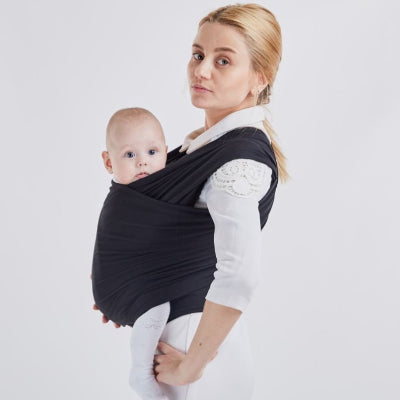 Bébé porté en position physiologique dans une écharpe de portage noire, genoux relevés et dos arrondi, pour un confort optimal.