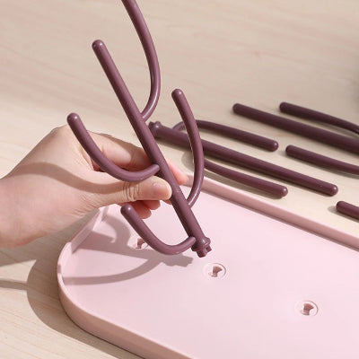 Gros plan sur le montage facile de l’égouttoir biberon BiberZen™, avec branche cactus en cours d’insertion sur le plateau, illustrant sa praticité.