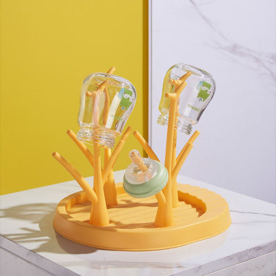 Égouttoir biberon jaune vif avec structure en branches, idéal pour sécher deux biberons et une tétine simultanément, dans une cuisine colorée.