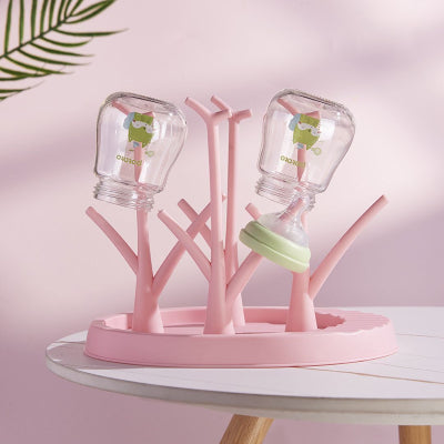 Égouttoir biberon rose pastel en usage, équipé de deux biberons et une tétine, parfait pour une organisation hygiénique et esthétique du coin repas bébé.