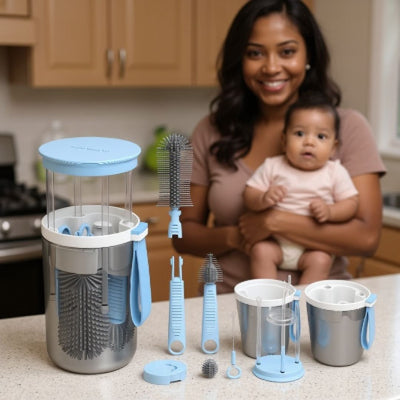 Goupillon biberon electrique TwistBébé bleu avec kit complet de nettoyage en silicone et distributeur de savon, présenté sur un plan de travail avec une maman et son bébé en arriÚre-plan.