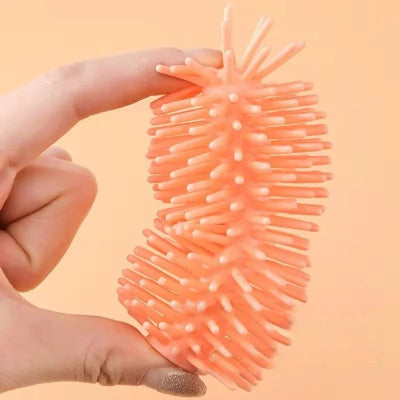 Détail de la matière souple du goupillon biberon montrant sa flexibilité entre deux doigts, garantissant un lavage doux et efficace des biberons.