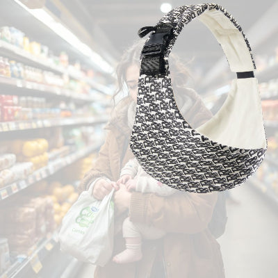 Maman en manteau portant son bébé à bras dans un rayon de supermarché, tenant un sac de courses, illustrant l’absence d’écharpe de portage.