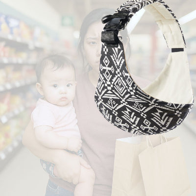 Jeune maman portant son bébé au supermarché sans écharpe de portage, visiblement fatiguée, tenant des sacs en main.
