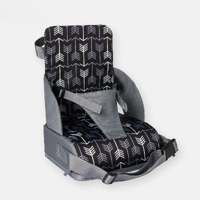 Gros plan sur un rehausseur chaise pliable motif flèches gris et noir, harnais ajustable et sangles de fixation pour chaise standard.