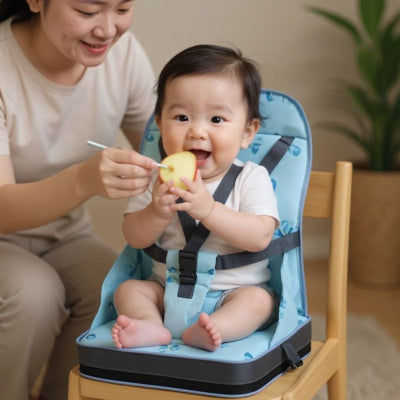 Bébé assis sur un coussin rehausseur chaise enfant bleu, installé à table et nourri par sa maman, harnais réglable pour plus de sécurité et stabilité.