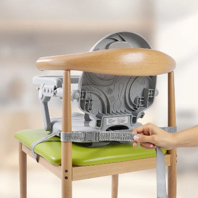 Réhausseur de chaise enfant installé dans le salon, bébé joue avec des blocs de construction sous le regard attentif de son papa.