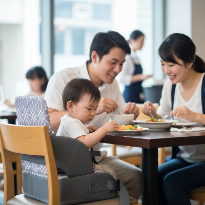 Bébé asiatique installé dans un rehausseur de chaise pour bébé bleu, buvant son biberon avec son papa, siège bébé pour table stable et confortable.