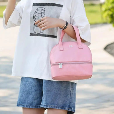 Sac isotherme bébé rose porté à la main par une jeune maman lors d'une promenade, pratique pour les sorties quotidiennes avec bébé.